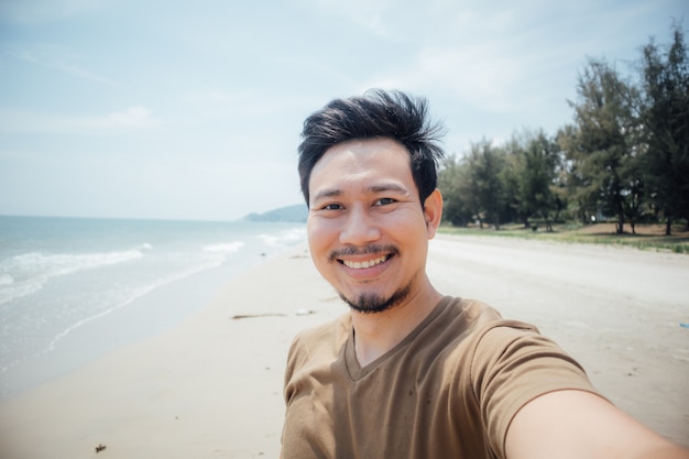 Cara alegre e feliz do selfie do homem ele mesmo na praia.