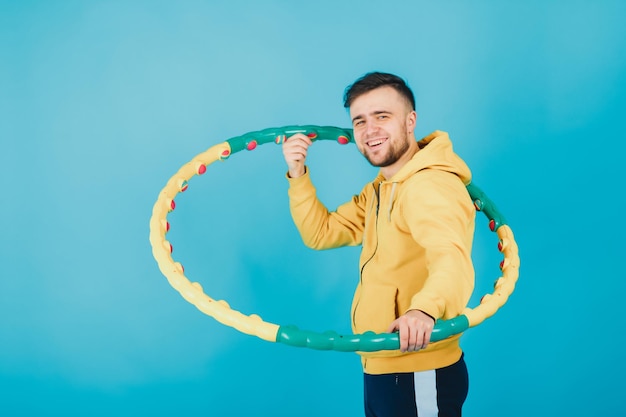 Cara alegre em uma blusa amarela com um bambolê mostra um gosto em um fundo azul