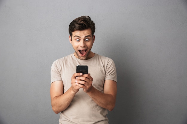 Cara alegre feliz segurando o smartphone e gritando de emoção