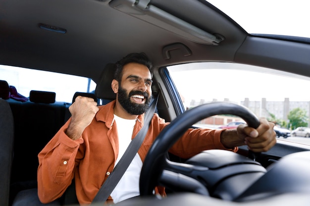 Cara animado do Oriente Médio sentado no carro gesticulando sim