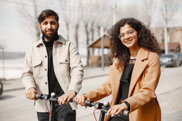 Cara anindian garota europeia andar de scooters e sorrir.