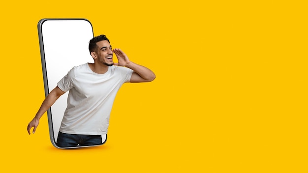 Cara árabe em pé no smartphone com tela vazia fazendo anúncio