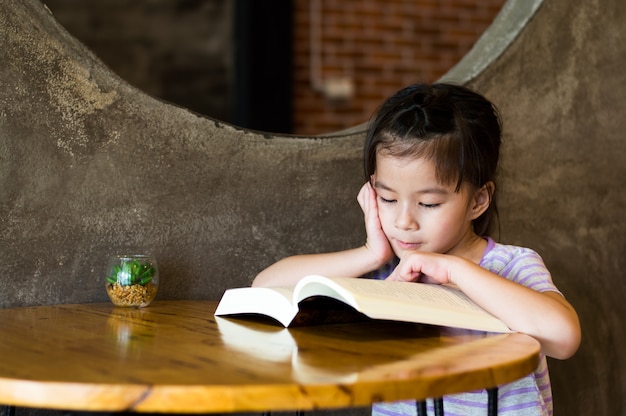 La cara asiática feliz de la muchacha leyó el foco selectivo del libro. Muchacha linda con sonrisa grande.