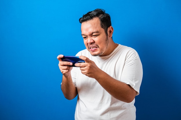 Cara asiático gordo e irritado jogando no tablet smartphone