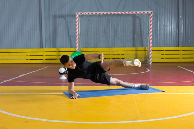 Cara atlético em roupas esportivas e rastreador de fitness fazendo exercícios no ginásio.