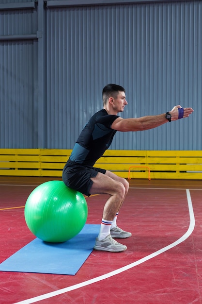 Cara atlético em roupas esportivas e rastreador de fitness fazendo exercícios no ginásio