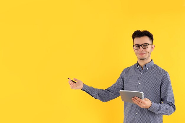 Cara atraente com caderno e caneta em fundo amarelo