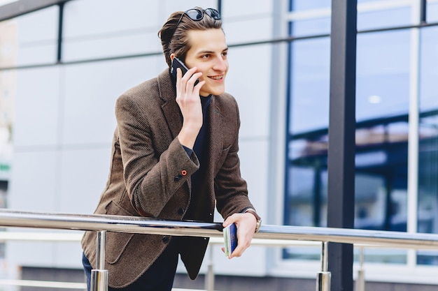 Cara atraente elegante na jaqueta com passaporte de telefone e bilhetes