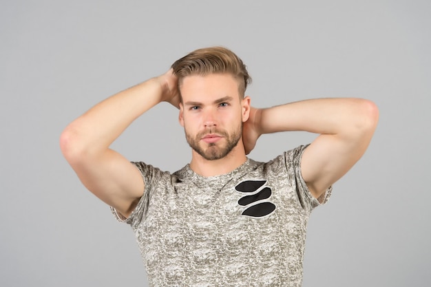 Cara barbudo atraente com penteado Homem barbudo rosto estrito desfrutar de frescura do cabelo fundo cinza Conceito de cuidados com o cabelo Homem com barba cara não barbeado bonito e bem cuidado tocando o cabelo