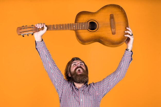 Cara barbudo bonito com cabelo estiloso tocando violão músico