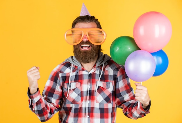 Cara barbudo estiloso com penteado moderno usa camisa quadriculada segura festa de balões de festa