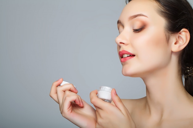 Cara de la belleza de la mujer con crema cosmética en cara