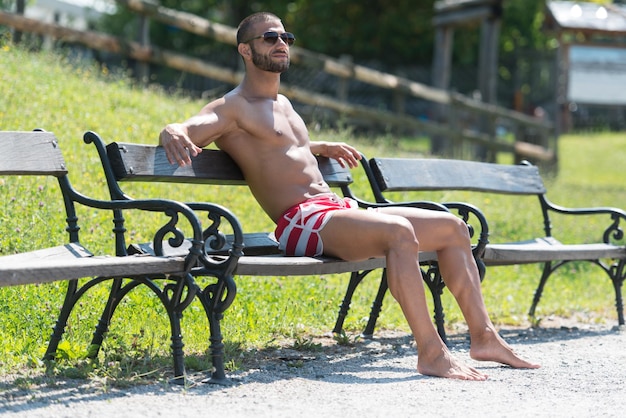 Cara bonito descansando no banco ao ar livre