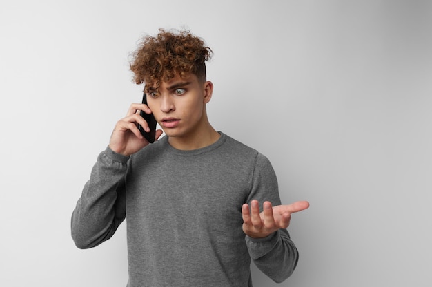 Cara bonito falando ao telefone posando fundo isolado de emoções