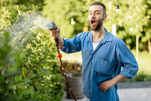 Cara bonito, regando a cerca verde no jardim