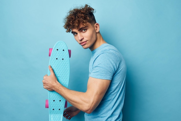 Cara bonito skate na mão em camiseta azul estilo de vida inalterado