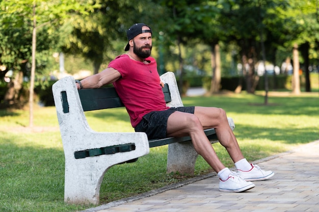 Cara bonito sorridente descansando no banco ao ar livre