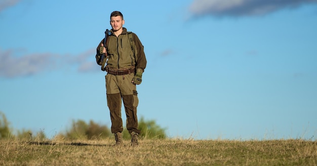 Cara caçando ambiente natural Arma de caça arma ou rifle Passatempo de caça Atividade de passatempo masculino Caçador de homem carrega rifle fundo do céu azul Experiência e prática dão sucesso à caça