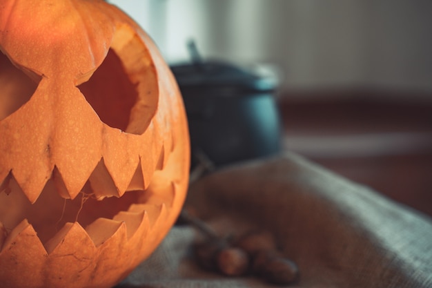 Cara de calabaza espeluznante de Halloween en una mesa con decoración Esqueleto velas nueces