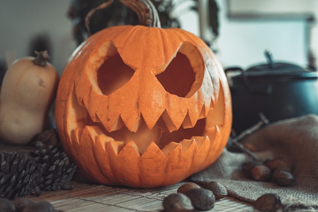 Cara de calabaza espeluznante de Halloween en una mesa con decoración Esqueleto velas nueces