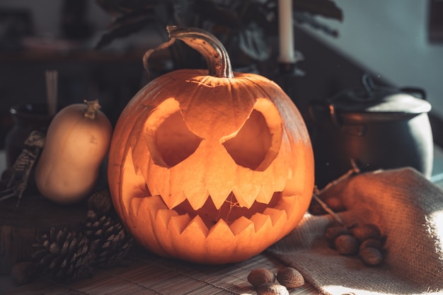 Cara de calabaza espeluznante de Halloween en una mesa con decoración Esqueleto velas nueces