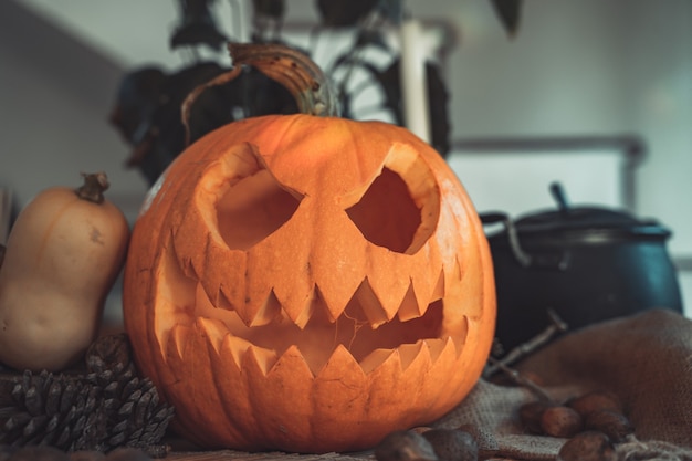 Cara de calabaza espeluznante de Halloween en una mesa con decoración Esqueleto velas nueces