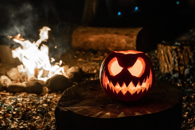 Cara de calabaza de Halloween con velas encendidas y campamento de fuego en el fondo Cara espeluznante y fuego de estanque