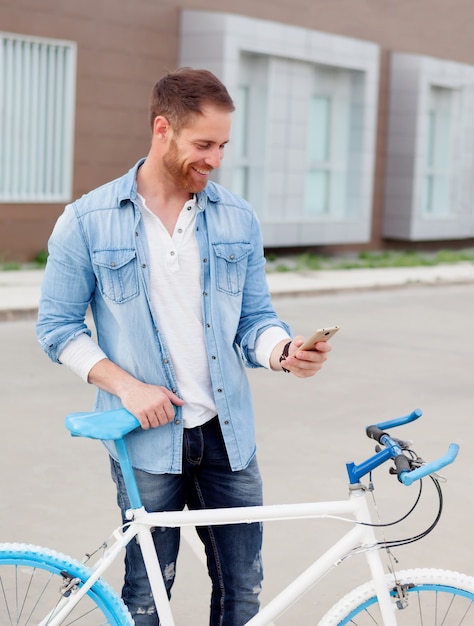 Cara casual ao lado de uma bicicleta vintage com o celular