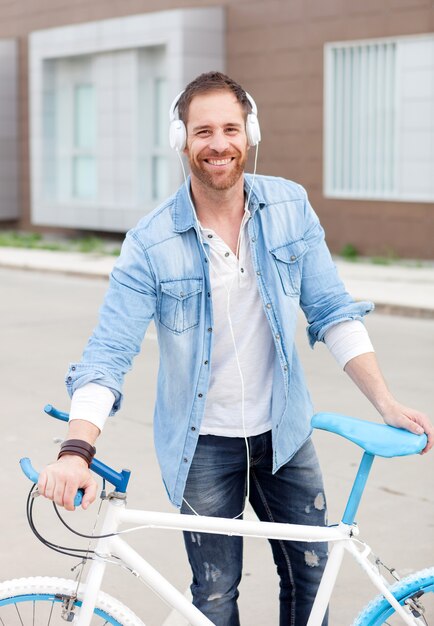 Cara casual com sua bicicleta na rua ouvindo música