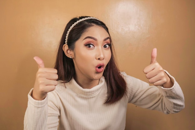 Cara de choque de una joven asiática con el signo OK usando una camisa blanca Concepto de publicidad