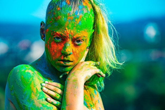 Cara colorida com respingo colorido de holi jovem alegre com tinta colorida em corpos se divertindo