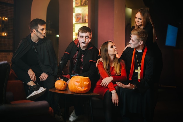 Foto cara com a fantasia de halloween do conde drácula está sentado com amigos em um café e olhando para a câmera