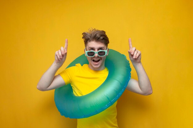 cara com anel inflável de natação mostra as mãos no fundo amarelo homem turista de férias