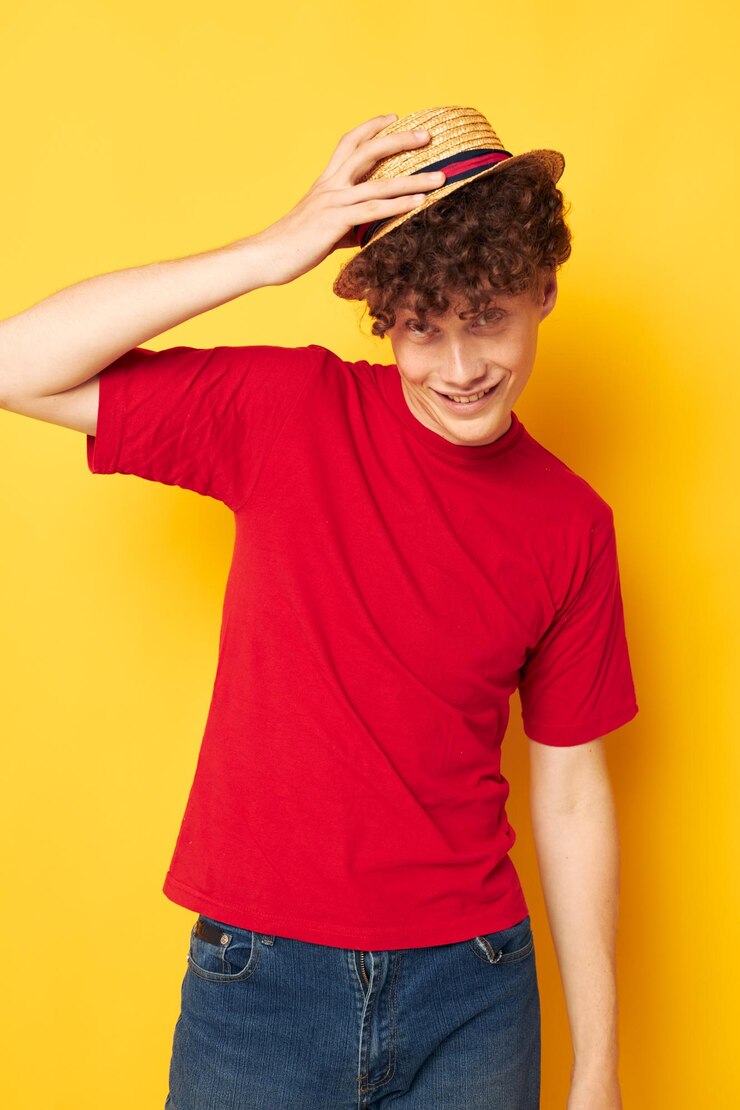 Cara com cabelo ruivo cacheado emoções camiseta vermelha chapéu estúdio fundo amarelo inalterado