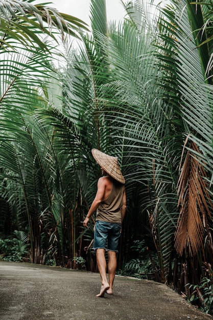 Cara com um chapéu de palha em ambiente tropical