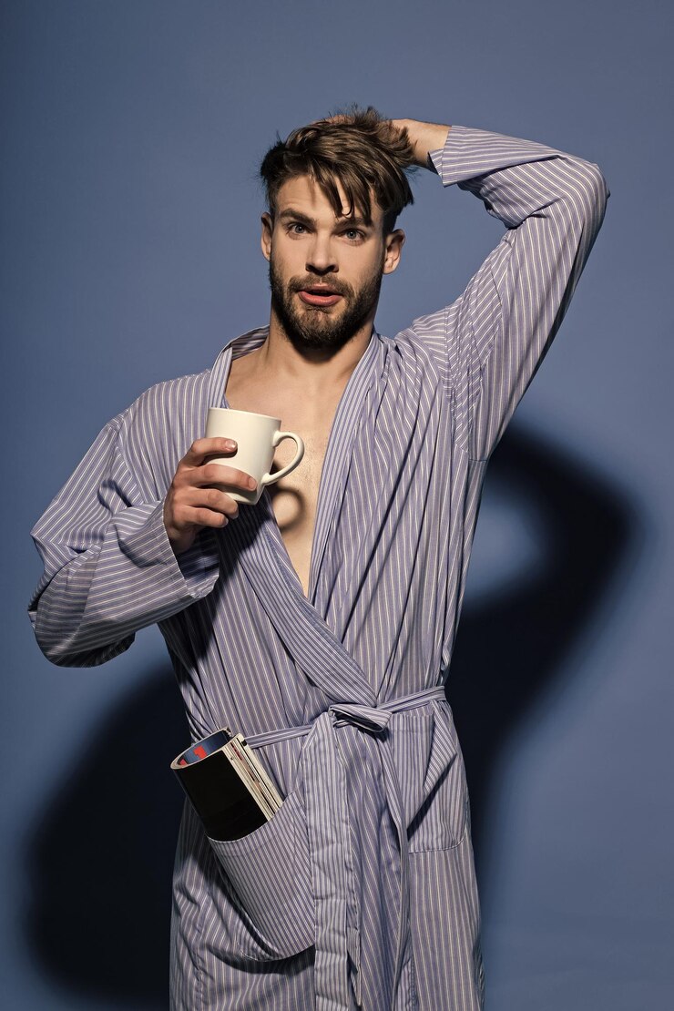 Foto cara com uma xícara de chá ou café, revista em roupão