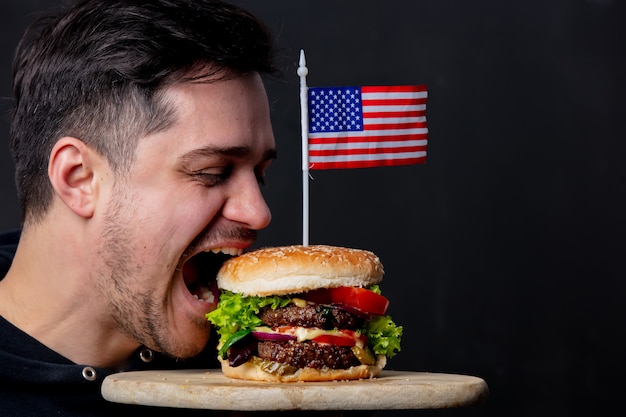 Cara comendo hambúrguer americano clássico