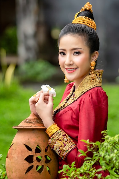 Cara da menina do Lao no vestido tradicional com a flor nacional de Laos, flor de Champa.