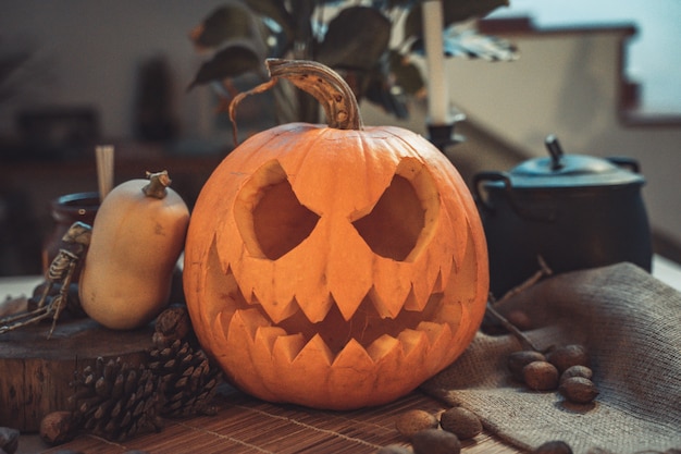 Cara de abóbora assustadora de Halloween em uma mesa com decoração nozes velas de esqueleto