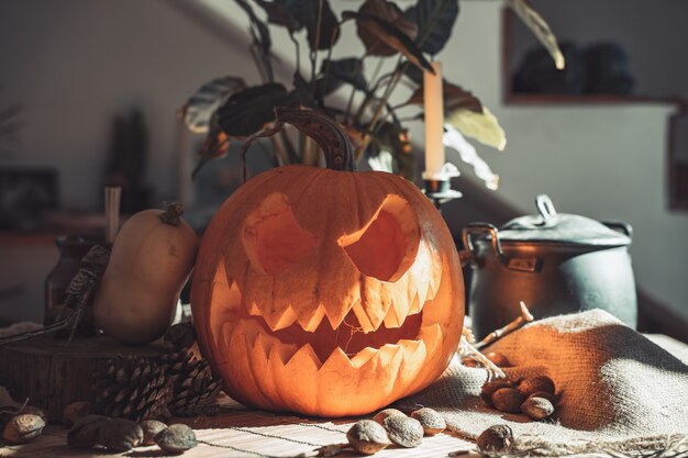 Cara de abóbora assustadora de Halloween em uma mesa com decoração nozes velas de esqueleto