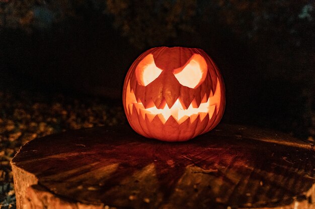 Cara de abóbora de halloween com vela acesa e acampamento de fogo ao fundo cara assustadora e fogo de lagoa