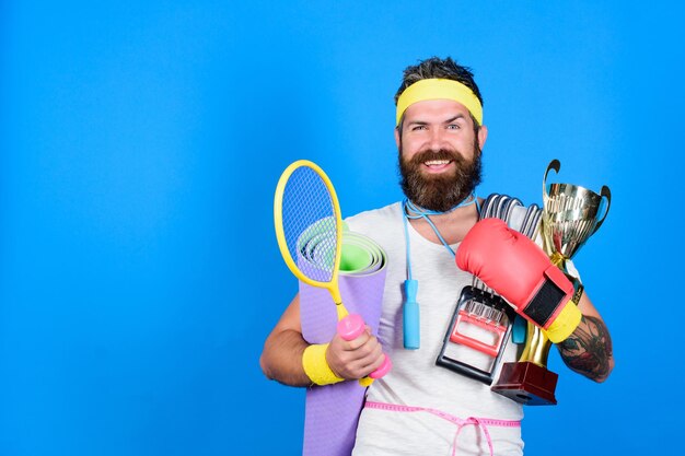 Cara de atleta motivado Instrutor de ginástica Atleta a caminho de um corpo mais saudável Hábitos saudáveis Treinamento de esportista fundo azul Treinamento de atleta com equipamentos esportivos Atleta de homem barbudo se exercitando