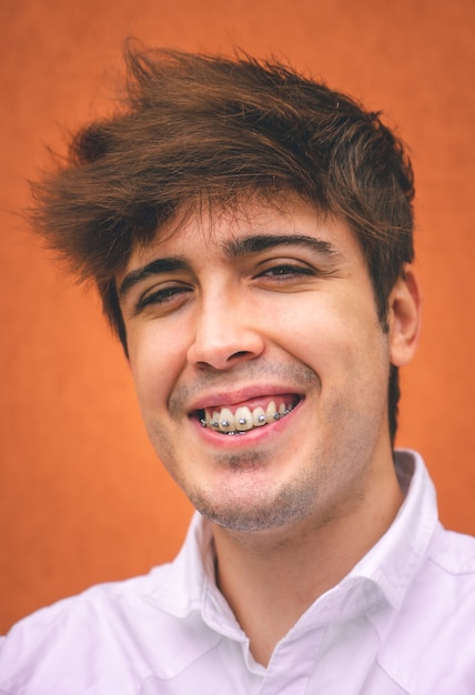 Cara de camisa branca sorrindo em uma parede laranja