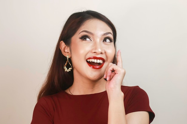 Cara de choque de uma jovem asiática vestindo uma camisa vermelha apontando para cima Conceito de anúncio