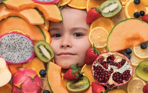 Foto cara de criança com frutas cara de criança com mistura de morango morango kiwi fruto do dragão