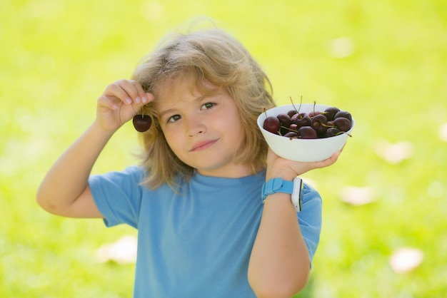 Cara de criança de verão colhendo e comendo cerejas maduras criança feliz segurando frutas frescas órgão saudável