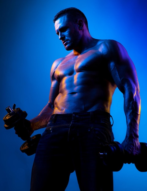 Cara de fisiculturista muscular fazendo exercícios com halteres isolados em neon azul Atleta nu com str
