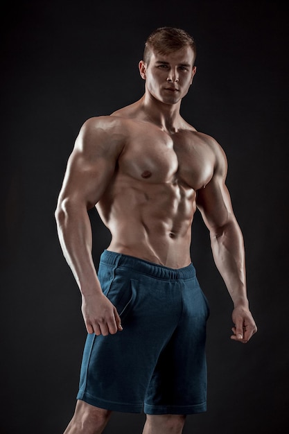 Cara de fisiculturista musculoso fazendo posando sobre fundo preto