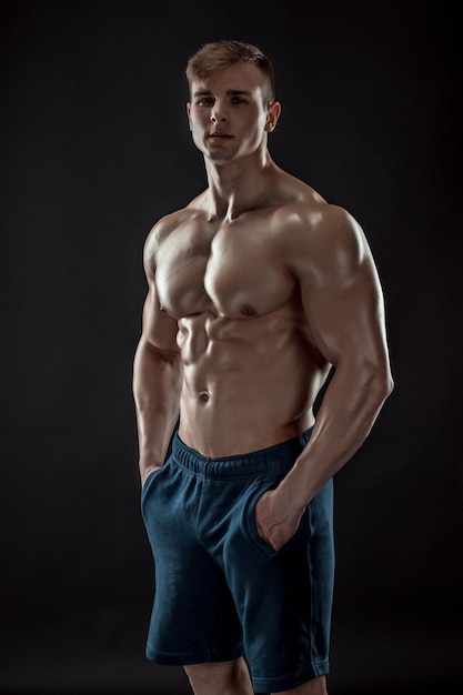 Cara de fisiculturista musculoso fazendo posando sobre fundo preto
