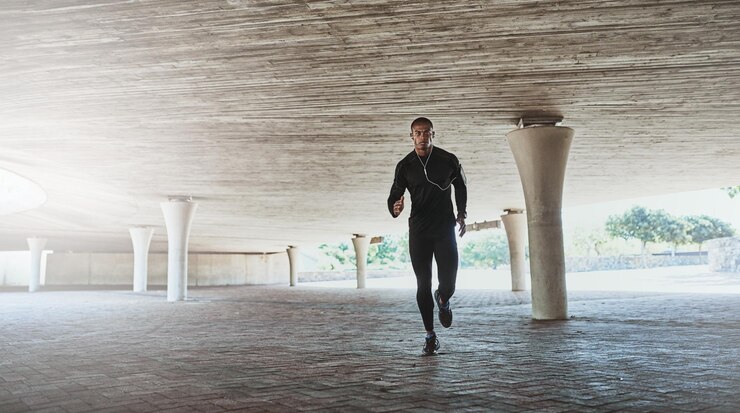 Foto cara de homem e corrida para fitness ao ar livre com música ouvindo podcast e exercício para corpo saudável atleta pessoa e fones de ouvido com rádio de áudio e som para treinamento de maratona no estacionamento